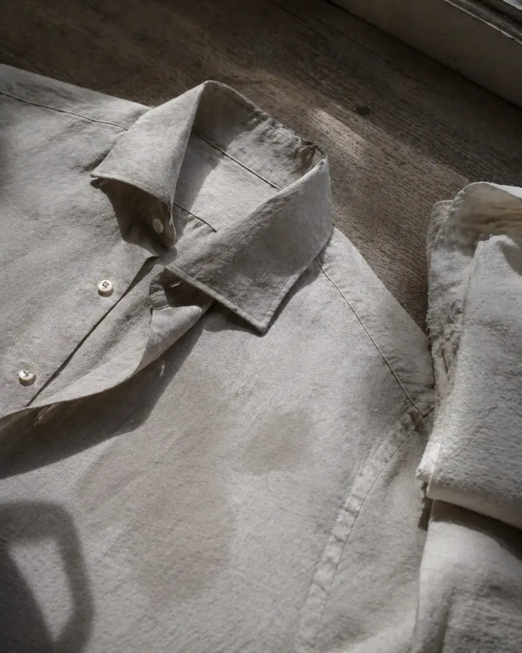 A cream linen collar pressed and settling on a wooden bench beside the iron.