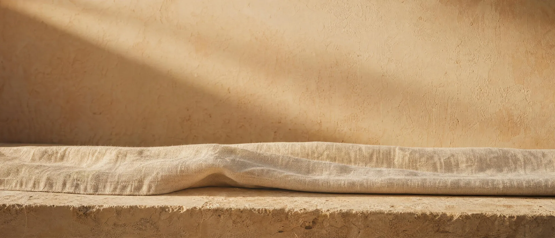 A folded length of cream linen on a stone slab in late afternoon light — the standard